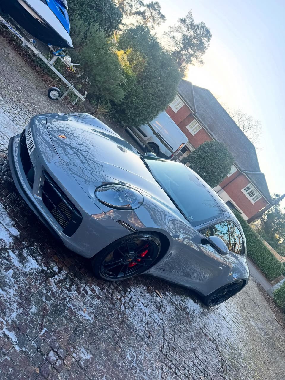 Grey Porsche 911 mid-wash on a wet driveway
